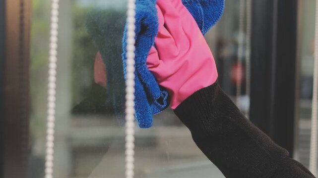 glass cleaner on a sheet of Cleaning glass window with a cloth special rag blue. close up hand