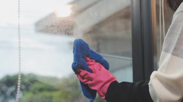glass cleaner on a sheet of Cleaning glass window with a cloth special rag blue. close up hand