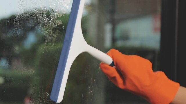 glass cleaner on a sheet of Cleaning glass window with a cloth special rag blue. close up hand