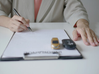 Fototapeta premium Businesswoman sits and signs documents or agreement for car sales, car insurance and car insurance concept