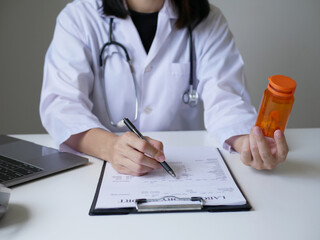 Fototapeta premium A female doctor reviews test results and diagnoses disease, records, prescribes medicine, and provides explanations. Recommend the use of medication Medical and wellness concept