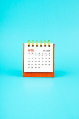 April 2025 white desk calendar on blue background.