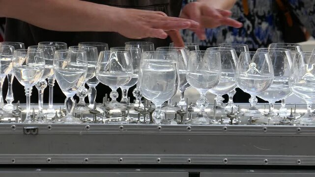 Glass harp water in wine glasses being played by outdoor performer