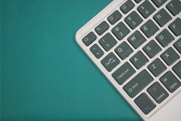 A modern keyboard with dark green keys and white lettering angles across a plain green background,...