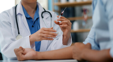 Doctor uses hypodermic needle and syringe to put a dose of medicine as treatment.