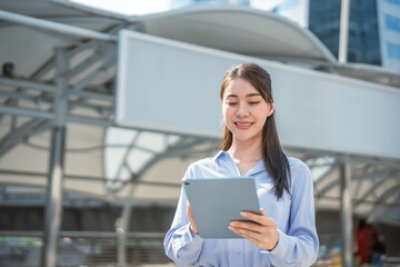 Asian young businesswoman using digital tablet while standing in the city.