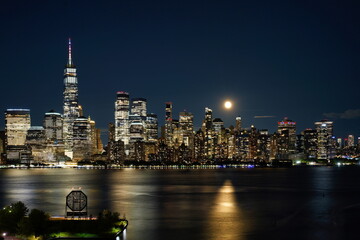 The lights of Manhattan skyscrapers on a moonlit night.