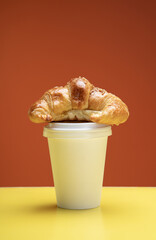 croissant, bean and coffee cup delivery on warm background