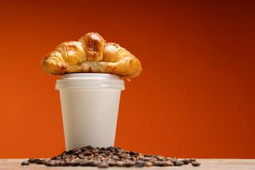 croissant, bean and coffee cup delivery on warm background