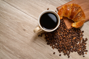 croissant and coffee beans on a wooden table. Free space for cafe menu
