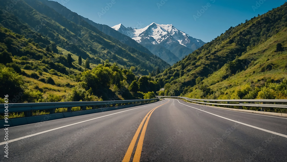 Wall mural panoramic view of a winding asphalt highway through snow-capped mountains under a clear summer sky