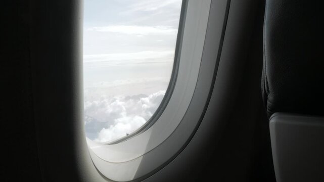  through the window of the airplane from inside cabin while flyiing climbing into the sky above the cloudscape outside in summer day,natural transportation holiday vacation background