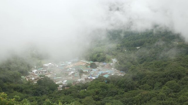 aerial view from doi pui view point to the local village among the mountain range hill valley with white cloud and fog over the village in winter daytime