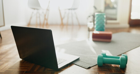 Laptop, mat and dumbbells with fitness equipment or interior on floor for online tutorial at home. Empty room or space with computer, technology or weights for health, wellness or tools for exercise