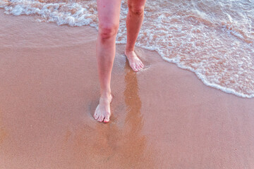 Beach - women's foot and the grains of sand.