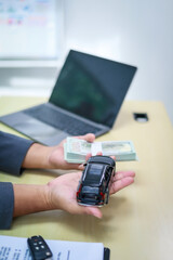 A businessman is working at his desk, focused on car financing, car sales, and insurance. He is analyzing customer data related to automobile financing and crafting strategies to improve sales