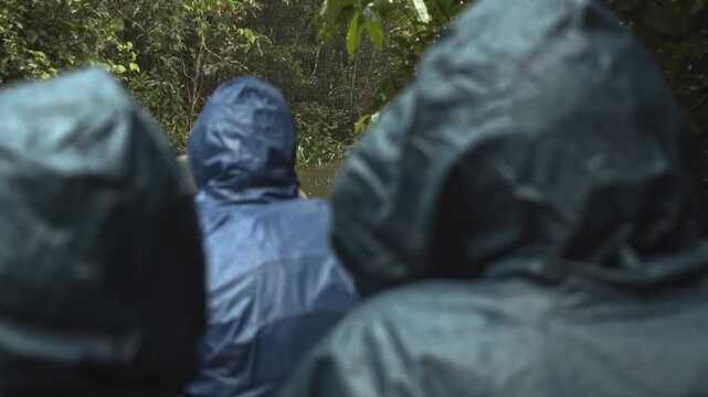 Group of tourist take a boat through a narrow river deep in rainforest.
