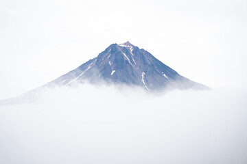The large Vilyuchinsky volcano has an edge visible in clouds and fog.