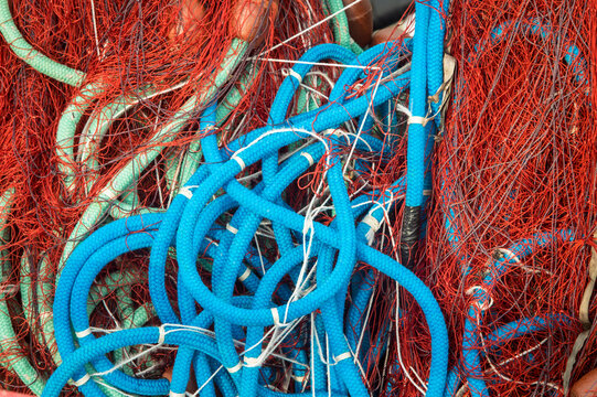 Dettaglio di alcune reti da pesca rosse e di corde azzurre all&rsquo;interno di un peschereccio