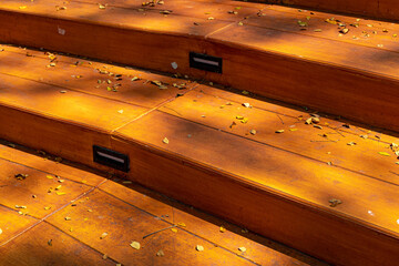 Close-up view of wooden stairs with dry leaf debris. stairs for the audience on one of the performance stages.