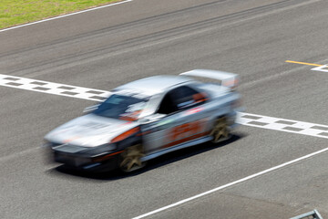 Motion blur race car racing on speed track, Car race on the international circuit race track crossing start and finish line, Race car crossing start and finish line, Target business achieve victory.