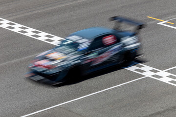 Motion blur race car racing on speed track, Car race on the international circuit race track crossing start and finish line, Race car crossing start and finish line, Target business achieve victory.