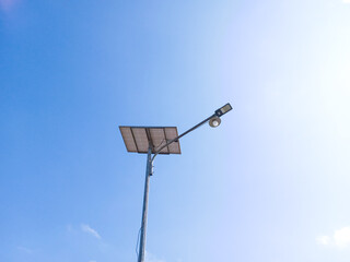 a solar powered street lamp against blue bright sky in Indonesia. innovative solar panel lights in sunny day. Bottom view