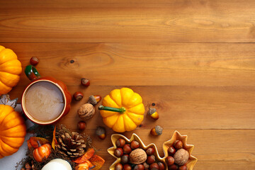 Autumn background with pumpkins, coffee cup, nuts, acorns on wooden desk. Top view fall, thanksgiving concept.