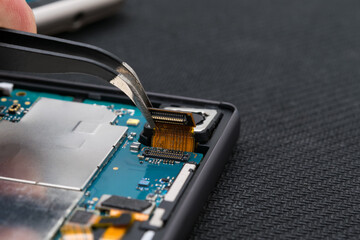 Repairing a mobile device using tweezers, side view