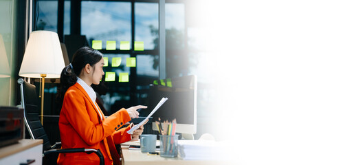 Business woman using tablet and laptop for doing math finance on an office desk, tax