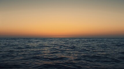 Obraz premium Seascape featuring an orange sky, capturing the serene beauty of the ocean as the sun sets, casting warm hues across the water's surface.