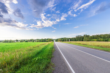 A road with a clear blue sky and a few trees in the background