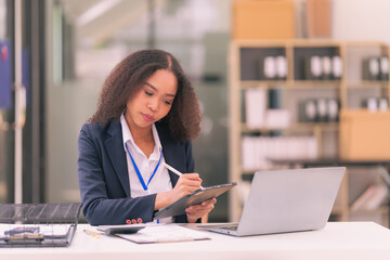 Female accountant uses calculator and holds pen for calculating business data. Business woman looks at laptop screen, calculates expenses, pays taxes online, financial documents.