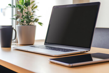 A modern workspace featuring laptop, tablet, coffee cup, and plant, conveying sense of productivity and calm.