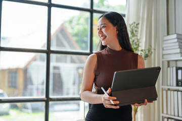 Beautiful Asian businesswoman stands and holds a laptop. Providing advice on business planning, finance, marketing to analyze customer groups in order to increase the amount of company growth.
