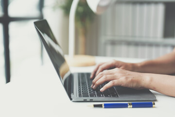 Asian businesswoman typing on a laptop computer keyboard to work on finance, taxes, reports, accounting, statistics, business growth and analytical research ideas.