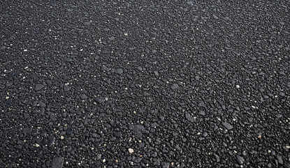 Close-up of a dark gravel texture with a few white stones scattered throughout.