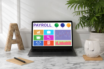 Laptop with payroll data on screen on table