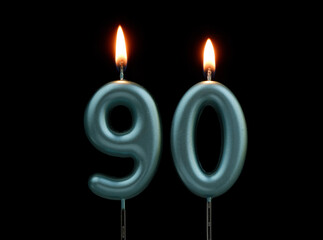 Burning blue birthday candles isolated on black background, number 90