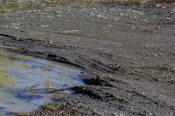 dirty broken rural road with deep tire tracks