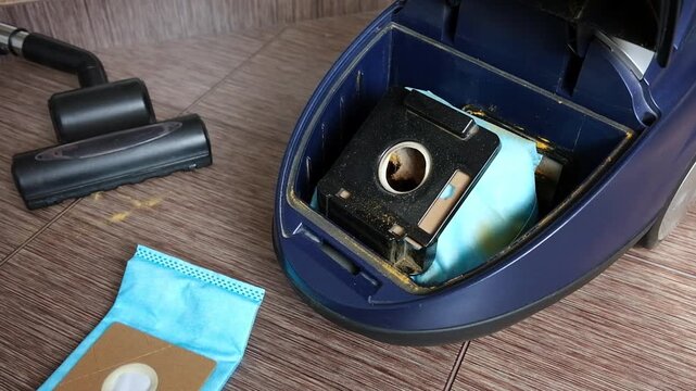 Close-up of open home vacuum cleaner and new clean cleaning bag.