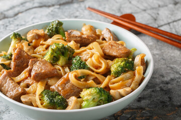 Asian style beef, noodles, mushrooms and broccoli in one bowl close-up on table. Horizontal