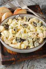 Winter chicken prune salad with boiled eggs and fresh cucumber seasoned with mayonnaise close-up in a bowl on a wooden board. Vertical