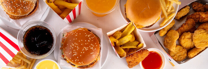 Fast food delivery menu background with various burgers, cheeseburger, nuggets, french fries, fizzy soda drinks. Junk unhealthy fast food, Ultra processed food with low nutrition, high calories value