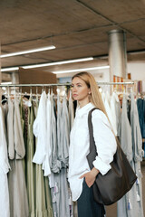 Middle aged woman runs across a rack of clothes in a shopping mall. Close-up of female hands plucked hanger choosing clothes in clothing store. Sale promotion and shopping concept.