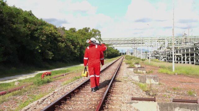 Team survey construction engineer with safety jacket use level survey camera. Engineer peering through a theodolite for check Raiway inside oil refinery plant.
