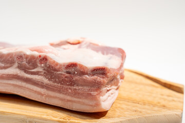 A piece of meat is on a wooden cutting board. The meat is cut into thin strips and he is fresh Pork meat isolated on a white background.