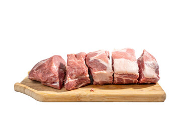 A slab of meat is cut into pieces and laid out on a wooden cutting board. The meat is raw and uncooked, and it is a variety of different cuts. Concept of preparation for cooking Pork meat isolated on 