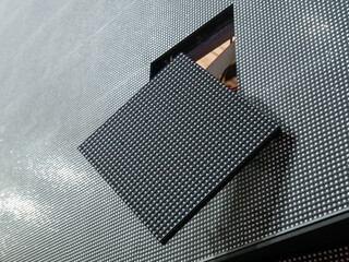 Close-up of a square LED module falling out of its place on the surface of a large LED screen