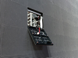 The LED module has fallen out of its place on the surface of the large LED screen and hangs on the wires